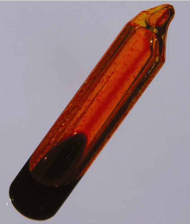 A glass container is shown that is filled with an orange-brown gas and a small amount of dark orange liquid.